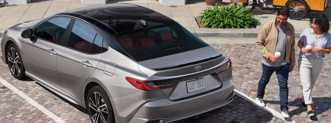 A couple walking by a 2025 Toyota Camry