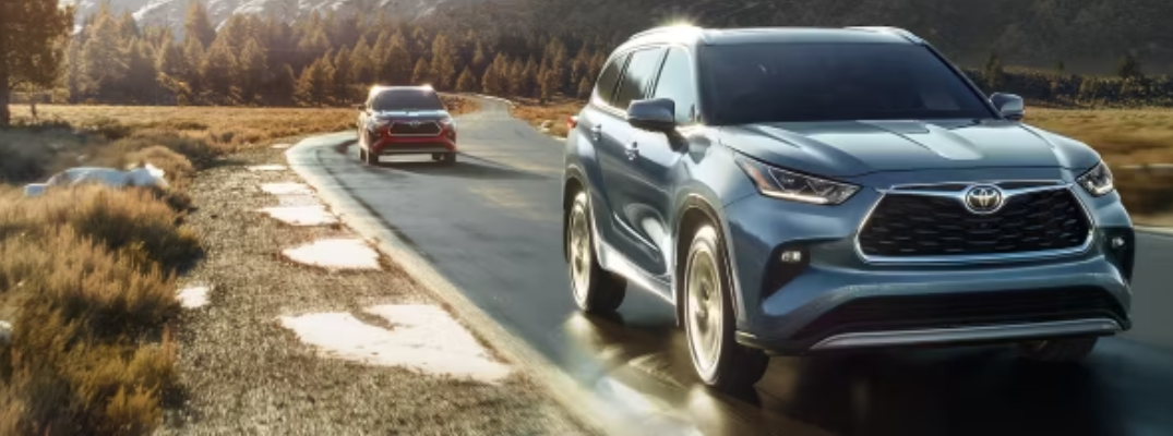 Two Toyota SUVs driving down a rural road.